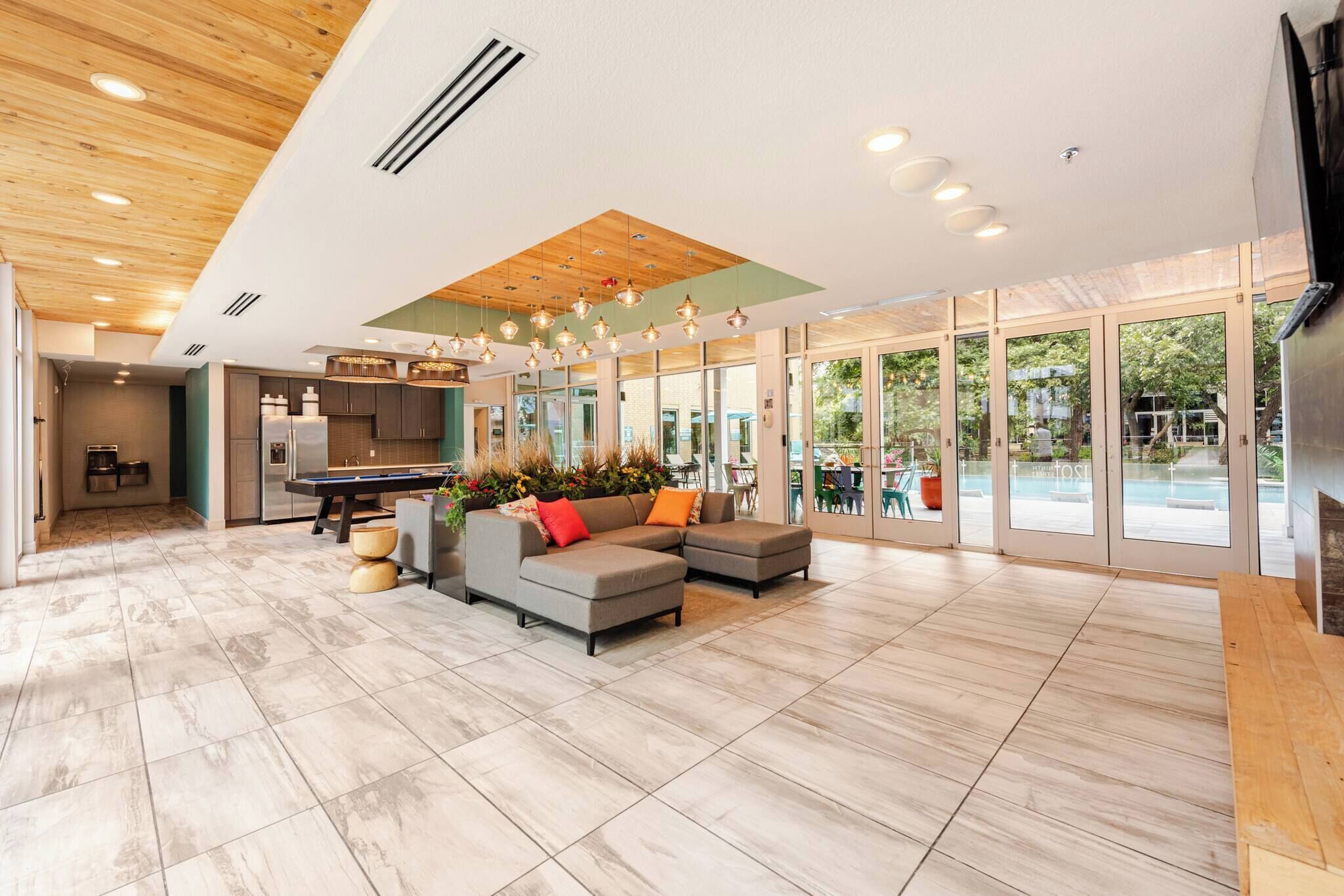 A spacious living area with a modern kitchen, large windows, and a pool view.