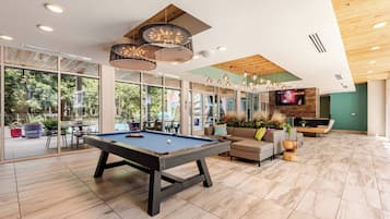 Un grand espace intérieur comprenant une table de billard, des sièges et un téléviseur.