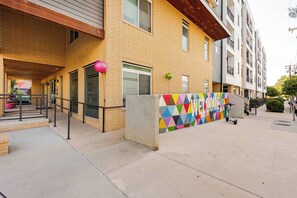 A multi-story building with a brick facade, a colorful geometric wall, and a scooter parked outside. - Riverwalk Downtown Luxury Pool & Free Parking (San Antonio)