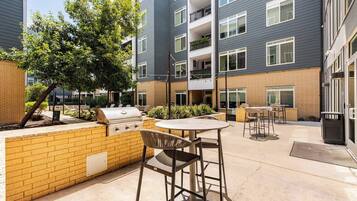 A courtyard with a barbecue grill, outdoor seating, and a brick wall.