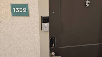 A door with a digital lock and a keypad, a doorbell, and a number plate '1339' on the wall.