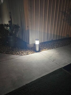 Un chemin menant à un bâtiment, avec un lampadaire et un pot de fleurs.