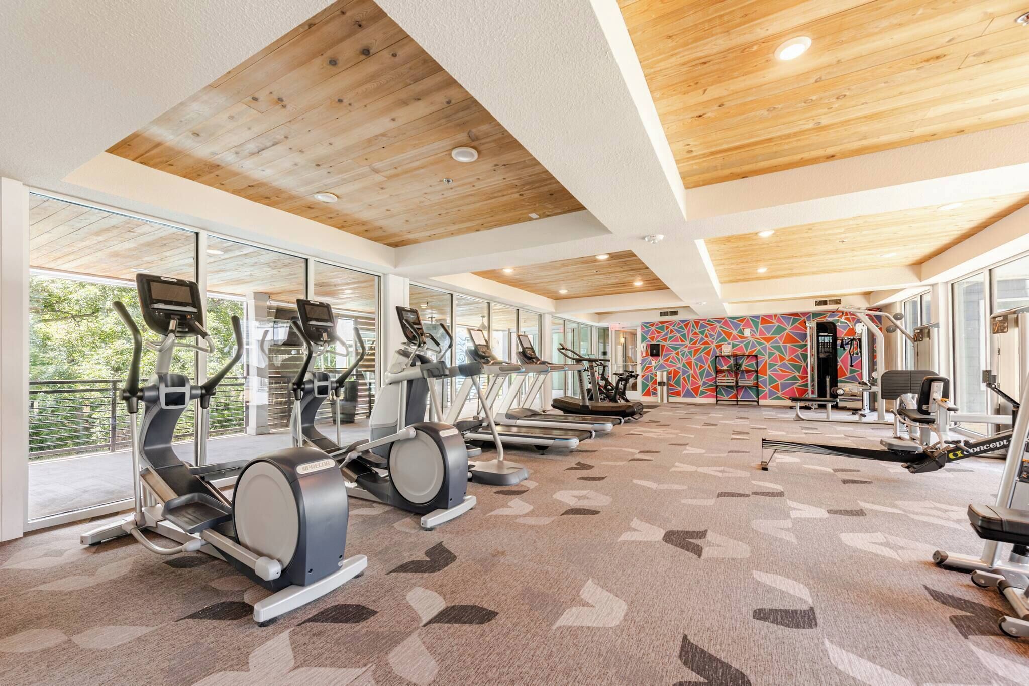 Une salle de sport équipée de tapis de course, de vélos elliptiques et d'appareils de musculation.