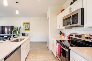Uma cozinha moderna com uma ilha grande, eletrodomésticos de aço inoxidável e uma televisão de tela plana.