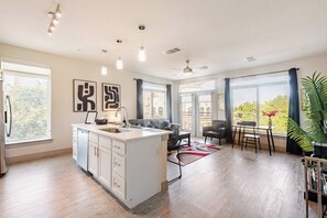A modern kitchen with a central island, a dining area with a table and chairs, and large windows with curtains. - Riverwalk Downtown Luxury Pool & Free Parking (San Antonio)