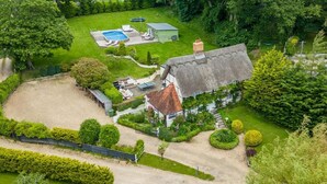 A large house with a thatched roof, a swimming pool, and a well-maintained garden. - 6 Bed in Lymington (oc-56765) (Boldre)