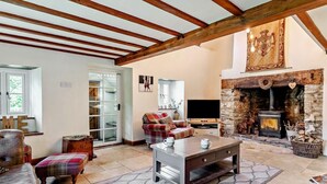A cozy living room with a stone fireplace, a television, and a comfortable seating area. - 3 Bed in Crickhowell (oc-56811) (Llangynidr)