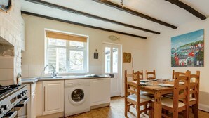 Una cocina con lavadora, sillas de madera y una mesa de comedor.