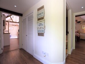 A hallway with a wall-mounted sign listing cottage rules, a door, and a glimpse of a bedroom with a bed and dresser. - 1 Bed in Dereham (oc-57021) (Mattishall)