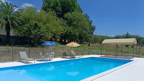 Una piscina rectangular con superficie de agua azul cristalina, rodeada por un deck de baldosas blancas.