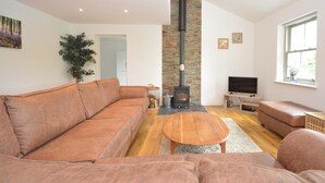 Een moderne woonkamer met een modulaire bank, een open haard, een televisie en een raam.