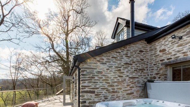 Een stenen gebouw met een hottub, een overdekt terras en uitzicht op het platteland.