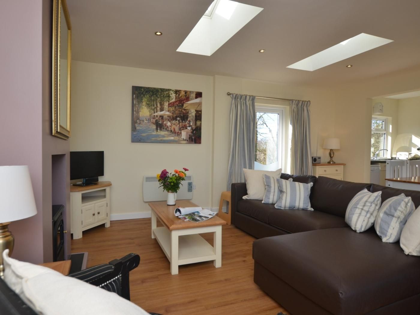 A living room with a sofa, a television, a small table with a vase, and a painting on the wall.