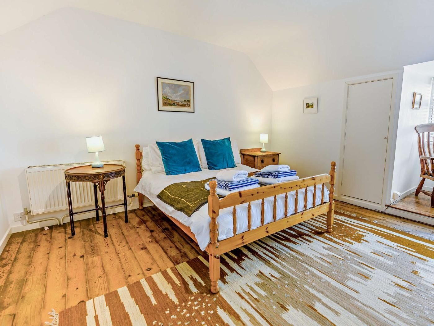 A bedroom with a wooden bed, two bedside tables, a radiator, and a patterned rug.