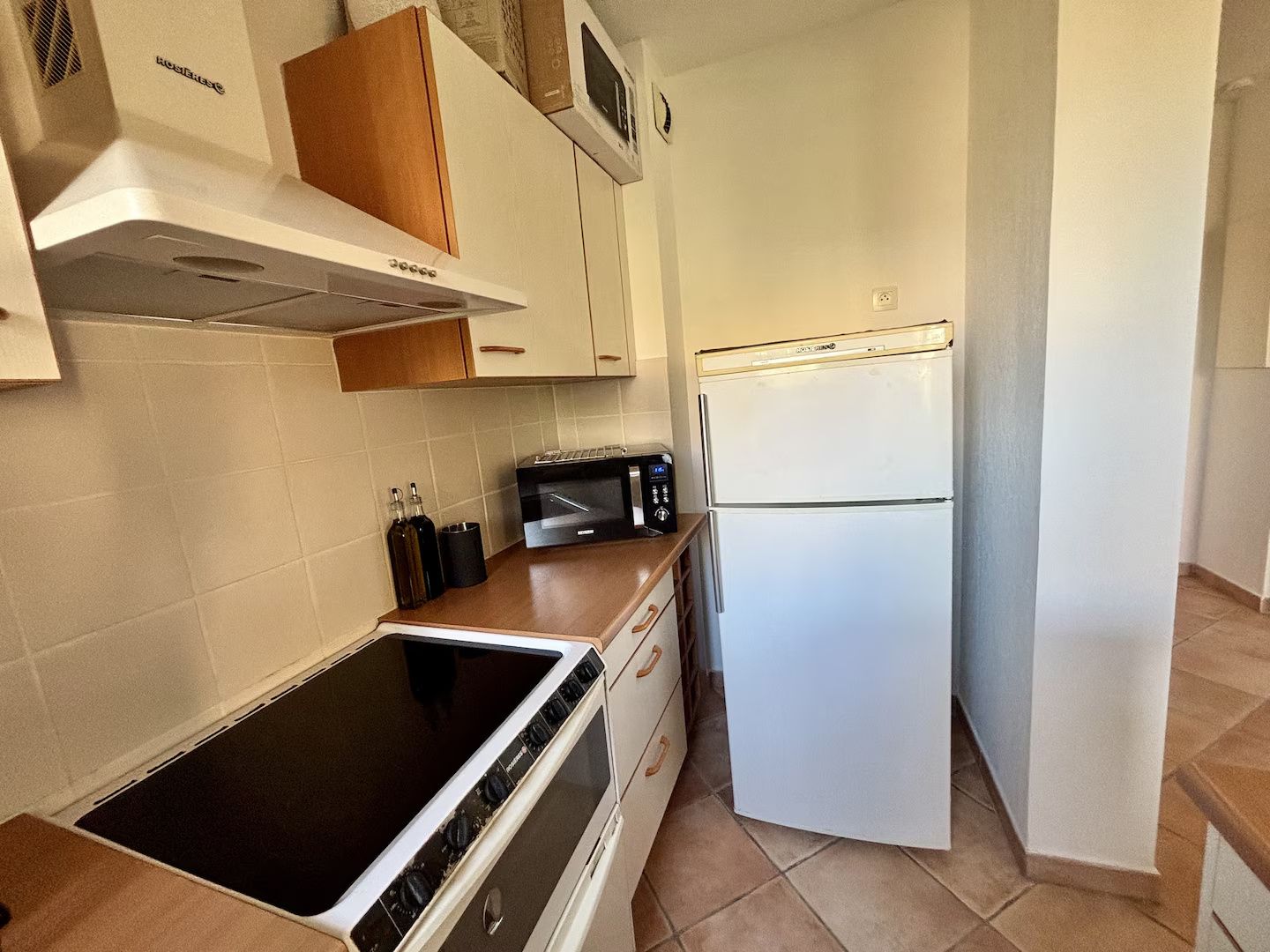A compact kitchen with a stove, microwave, and refrigerator.