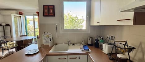 A compact kitchen with a window, a sink, and a dining area with chairs.