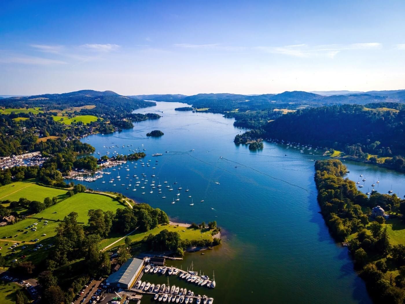 An aerial view of a lake surrounded by hills, with multiple boats docked at a marina.