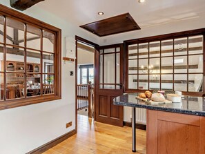 Una cocina con armarios de madera, encimera de mármol y vistas amplias a través de grandes ventanales.