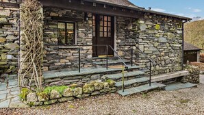 Una casa de piedra con puerta de madera, una ventana y una escalera que lleva a la entrada.