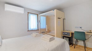 Habitación de hotel con cama, escritorio, silla, armario y ventana con cortinas.