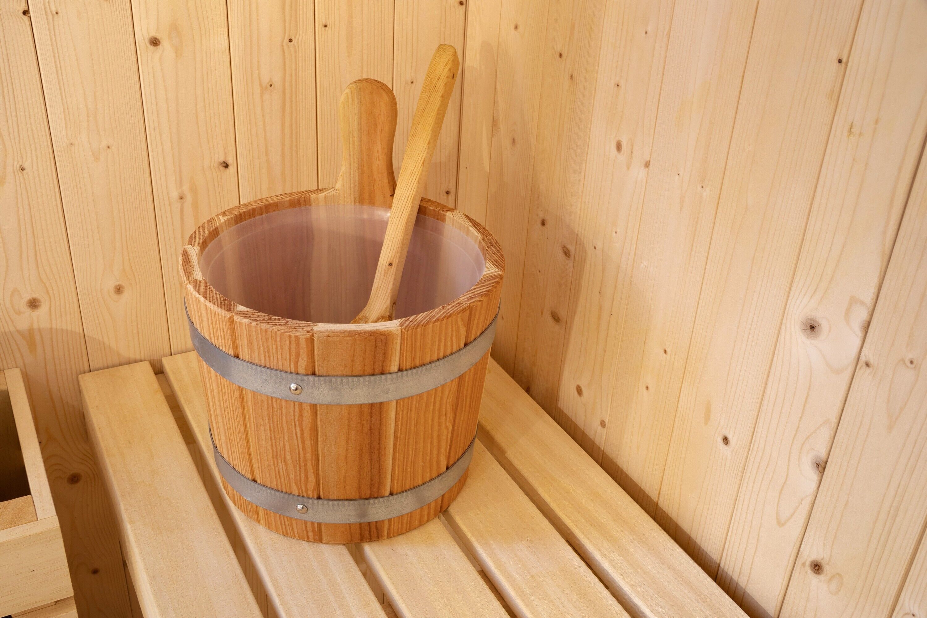 Una sauna de madera con un balde y un mazo de madera.