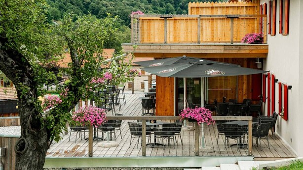 A restaurant with outdoor seating, wooden deck, and a view of the surrounding area.