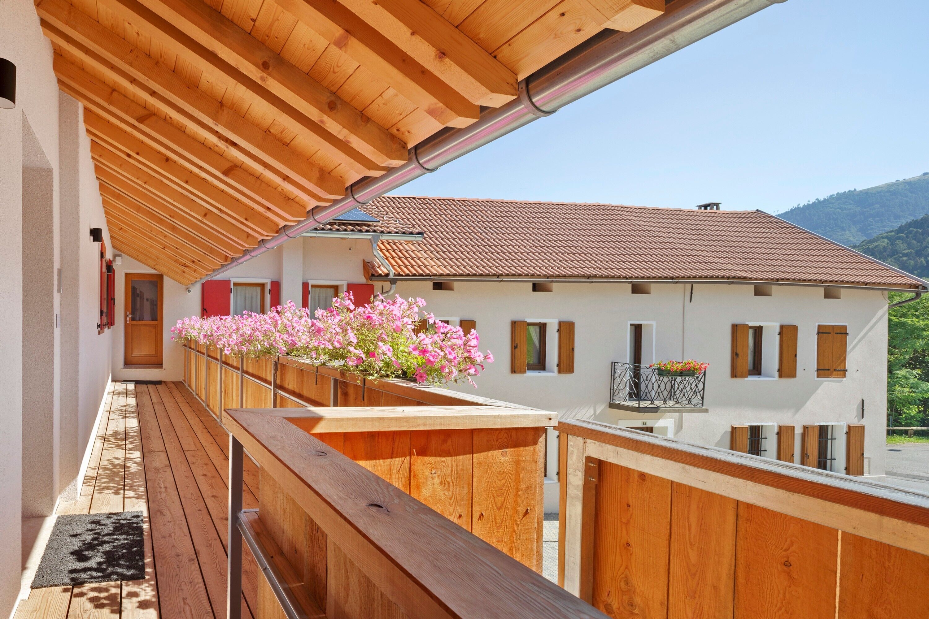 En träbalkong med utsikt över ett hus och berg.