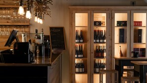 A bar area with wooden shelves, a counter, and a seating area.