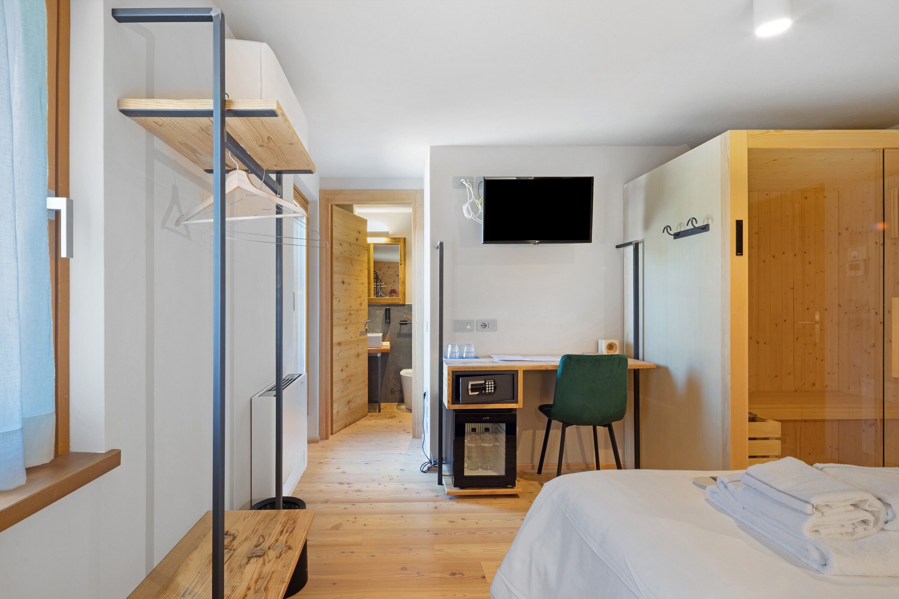 Une chambre d’hôtel moderne équipée d’un lit, d’un bureau, d’une chaise, d’une télévision et d’une armoire.