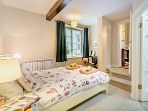 A bedroom with a bed, a radiator, a window with curtains, a lamp, and a door leading to another room. - 2 Bed in Keswick (oc-lcc19) (Underskiddaw)