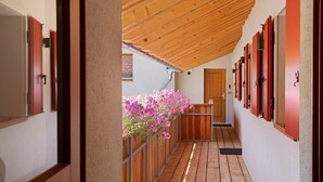 A corridor with wooden flooring, a sloped ceiling, and a wooden door at the end.