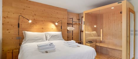 Une chambre à coucher aux murs lambrissés, avec un lit, des lampes de chevet et un dressing.