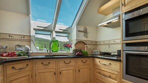 A kitchen with wooden cabinets, a built-in oven, a microwave, and a window with a view of the outdoors. - 1 Bed in Coniston (oc-lcc37) (Blawith)