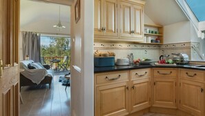 A kitchen with wooden cabinets, a dining area with a table and chairs, and a view of the outdoors. - 1 Bed in Coniston (oc-lcc37) (Blawith)