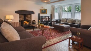 A cozy living room with a fireplace, sofas, a coffee table, and a television. - 4 Bed in Nr Hawkshead (oc-lcc33) (Near Sawrey)