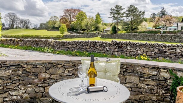 A stone wall, a table with a bottle and glasses, and a scenic view of a countryside landscape. - 4 Bed in Nr Hawkshead (oc-lcc33) (Near Sawrey)