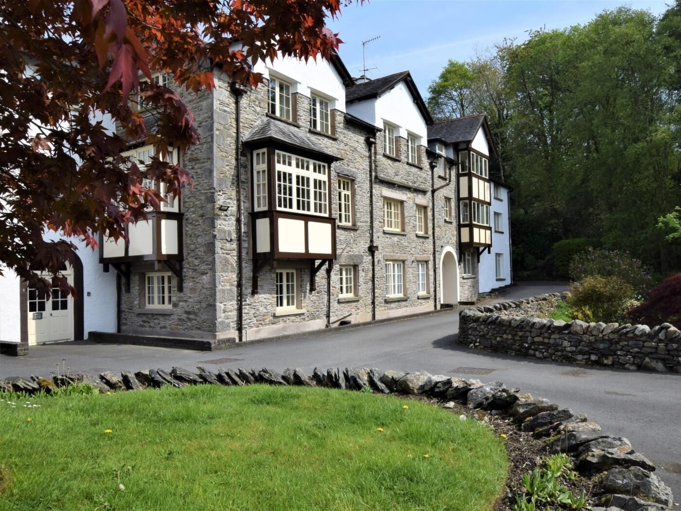 A traditional stone building with multiple windows and a stone wall in front.