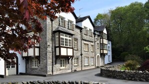 Un bâtiment traditionnel en pierre, doté de nombreuses fenêtres et d’un mur de pierre à l’avant.