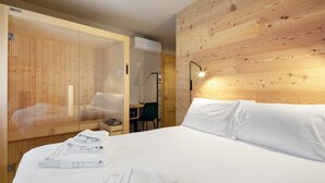 Une chambre d’hôtel avec un mur en bois, un lit avec du linge de maison blanc, un bureau avec une chaise et un appareil de climatisation visible.