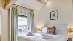 Une chambre à coucher avec un lit, des oreillers, une table de chevet, une lampe et un tableau encadré au mur.
