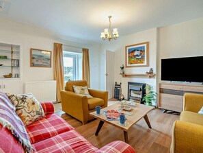 A living room with a sofa, armchair, coffee table, fireplace, television, and a bookshelf. - 2 Bed in Dundee (oc-58026) (Wellbank)
