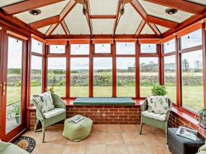 A conservatory with a brick bench, wicker chairs, and a view of the countryside. - 2 Bed in Dundee (oc-58026) (Wellbank)