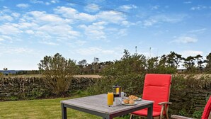 An outdoor seating area with a table and chairs, a stone wall, and a grassy field in the background. - 2 Bed in Dundee (oc-58026) (Wellbank)