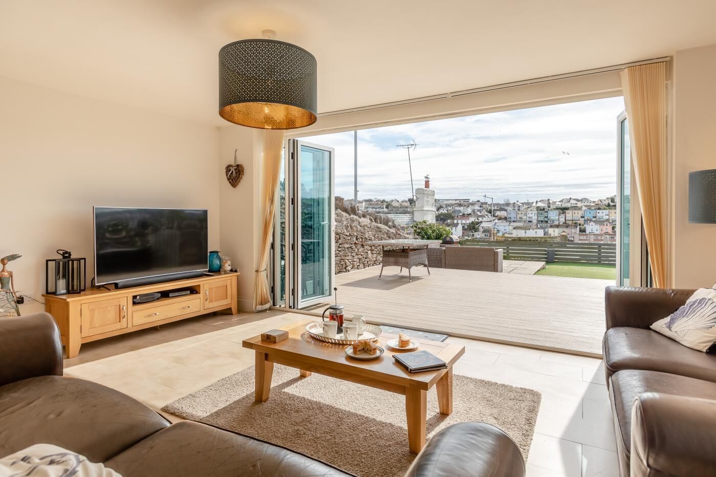 Ein Wohnzimmer mit Fernseher, Sofa, Couchtisch und Blick auf eine Stadtlandschaft durch große Fenster.