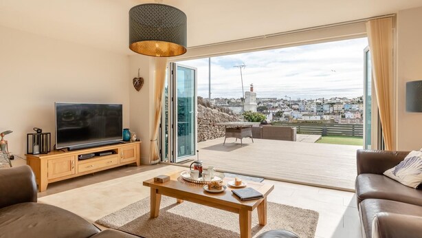 Ein Wohnzimmer mit Fernseher, Sofa, Couchtisch und Blick auf eine Stadtlandschaft durch große Fenster.