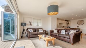 Ein modernes Wohnzimmer mit zwei Sofas, einem Couchtisch, einer Stehlampe und einem großen Fenster.