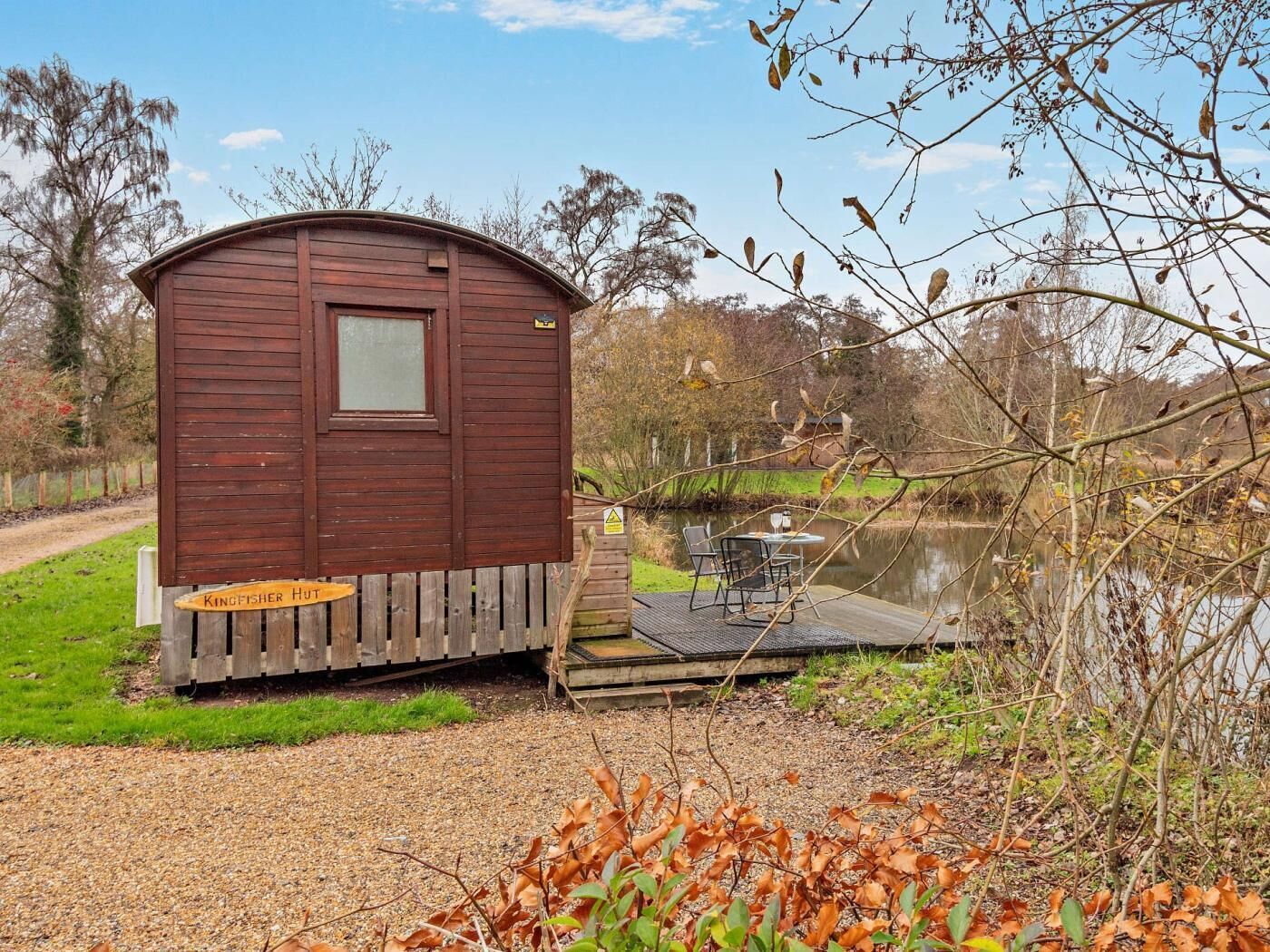 Une cabane en bois avec une petite terrasse et une table au bord d’un lac.