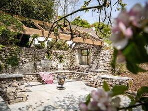 A stone building with a wooden pergola, a stone wall, and a tiled patio area. - 4 Bed in Buxton (oc-57687) (Priestcliffe)