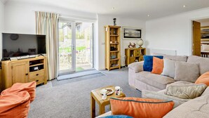 Ein Wohnzimmer mit Fernseher, Sofa, Couchtisch und Bücherregal.