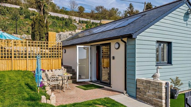 Ein Haus mit Terrasse, einem umzäunten Garten und einem kleinen Garten.